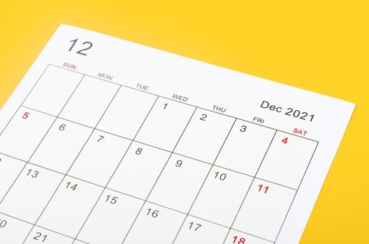 Close up December 2021 calendar sheet on yellow background.