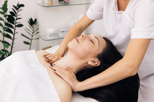 Cosmetologist is touching girl's face. Facial cleansing with professional cosmetic facial massage. Woman is having cosmetic treatment at spa salon.