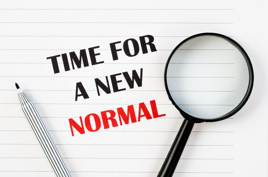 Time for a new normal with magnigying glass on paper. Life after pandemic concept.