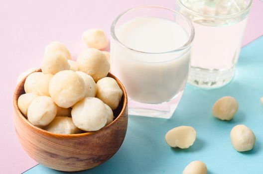 Macadamia milk in a glass and a bowl of macadamia nuts with oil on a beautiful background.