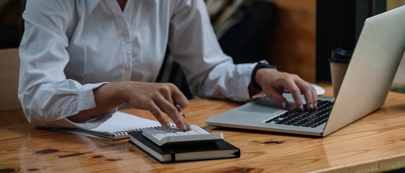 Close up accountant woman working about financial and analysis business document with calculator and holding glasses at his office to calculating expenses, Accounting concept