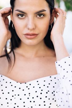 Front closeup portrait of young mixed race beauty american woman with long hair style standing on street near sakura trees, looking friendly at camera. Human face, ideal natural make up skin concept