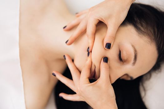 Close up of young girl receiving a facial massage and spa treatment for perfect skin in a luxury wellness center.