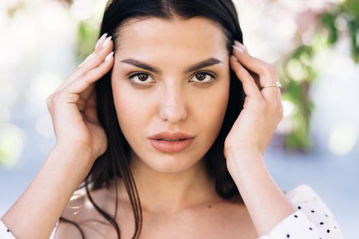 Face of beautiful soft woman with natural make-up looking at camera. Portrait young asian pretty brunette girl outside at sunshine. Etnnicity. People. Beauty.