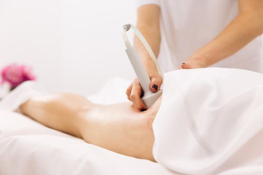 Woman getting anti-cellulite and anti-fat therapy. Female physiotherapist doing an anti-cellulite can massage of the buttocks and hips of a young woman. Care and maintenance of the health concept