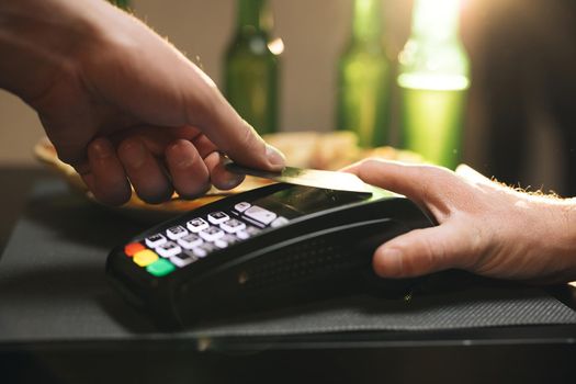 Financial success and safety. Close up of male hold in hand wireless modern bank payment terminal to process acquire credit card payments black card. Credit card machine for money transaction.