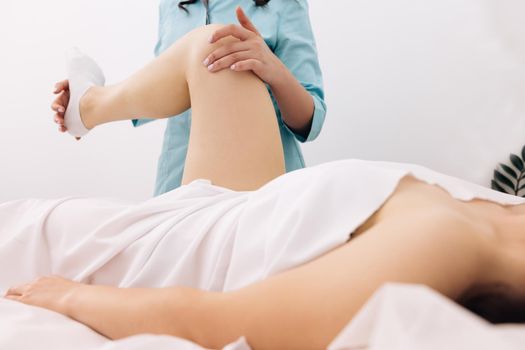 Physiotherapist stretching female patient on the bed in hospital - physical therapy concept. Professional Doctor in Modern Rehabilitation Clinic Rehabilitation After Injuries. Healthcare Concept