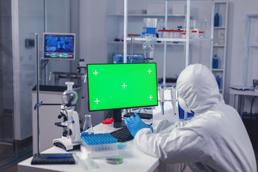 Medic uses computer with copy space available in moden laboratory during coronavirus. Team of microbiologists doing vaccine research writing on device with chroma key, isolated, mockup display.