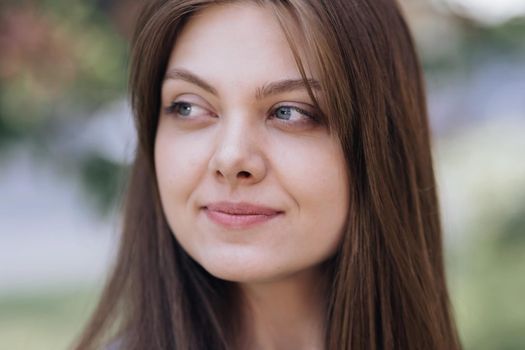 Beautiful face of tender attractive woman staying outside. Attractive young lady with her hair blowing in the wind. Perfect model with creative vivid makeup and pink lipstick on lips. Ethnicity.