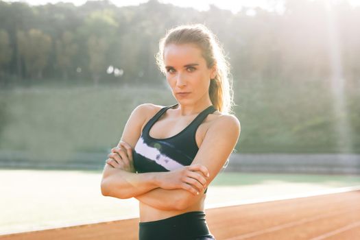 Nice girl resting outdoor after power workout and physical activity. Sports and workout. Portrait of beautiful woman in sport clothes professional athlete looking at camera after physical training.