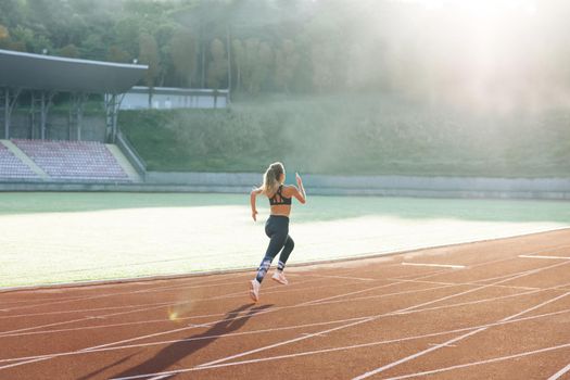 Female marathon runner on professional sports arena. Fitness woman racing at stadium. Female sprinter race on outdoor track arena. Motivated girl winning speed contest.