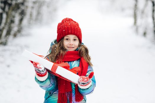 Child holding gift box and surprise face. Little girl with christmas box gift in winter outdoors on Xmas eve. Happy Little caucasian girl smile and holding gift box in Christmas day.