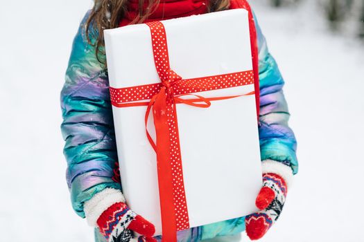 Little girl with christmas box gift in winter outdoors on Xmas eve. Happy Little girl holding gift box in Christmas day. Child holding gift box.