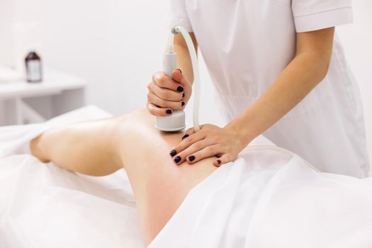 Woman getting anti-cellulite and anti-fat therapy in beauty salon. Hardware cosmetology. Body care. Spa treatment. Legs anti-cellulite procedures. woman health and beauty