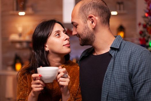 Portrait of happy family looking at each other celebrating christmas holiday together spending time together in xmas decorated kitchen. Joyful couple enjoying winter season.