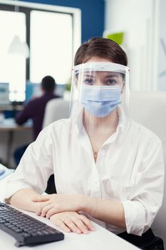 Close up of financial entrepreneur wearing face mask at workplace Business team working in financial company respecting social distance during global pandemic.