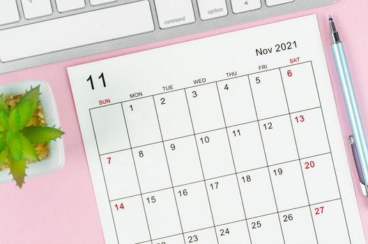 November 2021 calendar sheet with keyboard computer on pink background.