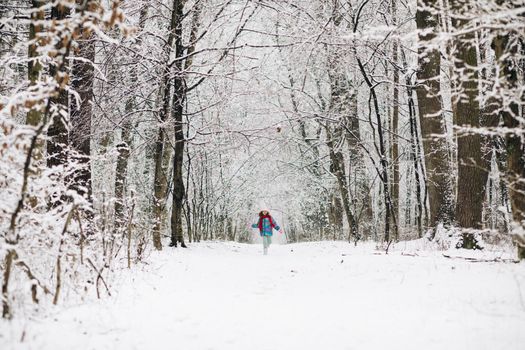 Child girl are having a fun running between snow trees in winter time, happiness concept. Happy girl running on snow in winter.