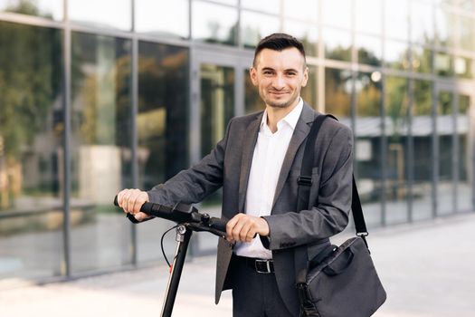 E-Scooter rider rent personal eco transport. Portrait of confident businessman standing with electric scooter and looking at camera. Technology, business, Internet app concept.