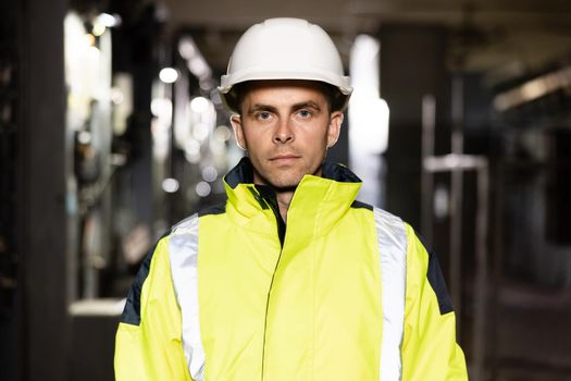 Happy Professional Heavy Industry Engineer Worker Wearing Uniform and Hard Hat in a Steel Factory. Smiling Caucasian Industrial Specialist Standing in a Metal Construction Manufacture.