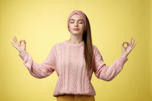 No stress. Pretty young female student not worry, releasing negative emotions during yoga training session standing in lotus pose, breathing smiling relieved happy, showing mudra sign feeling relaxed.