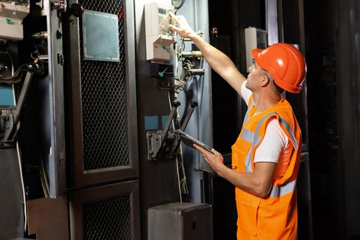 Engineer using digital tablet checking and inspecting at MDB panel working with electric switchboard to check range of voltage working in main distribution boards factory.