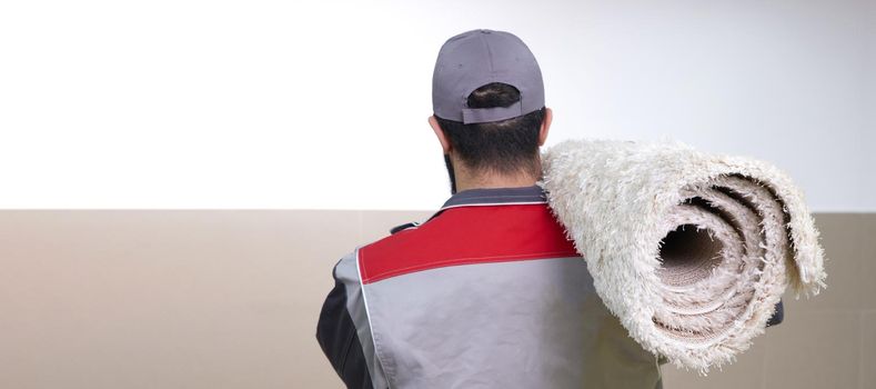 Rear view of man with a roll of carpet on a shoulder