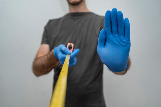 man with gloves holding tape measurer social distancing. High resolution photo