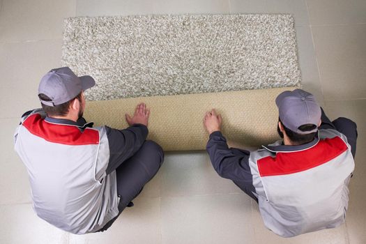 Male Worker Unrolling Carpet On Floor At Home