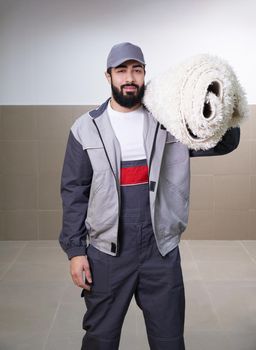 Man wearing a uniform standing with a roll of carpet on his shoulder