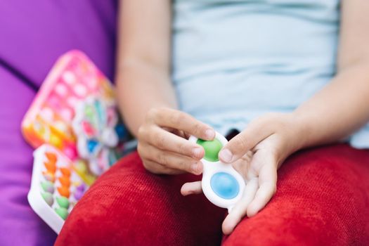 Pop it simple dimple popit anti-stress sensory toy for children. Girl hands playing with toy. Topview of playing a popular game with buttons, an anti-stress toy. Educational children's games.