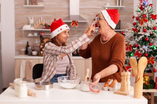 Family having fun together playing with flour while cooking homemade dessert making traditional cookies dough enjoying winter season in xmas decorated kitchen. Kid celebrating christmas holiday