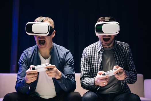 Young adults is playing video games at home. Emotional diverse gamers are holding joysticks and competition in intense video game on gaming console. They Plays with Wireless Controllers.