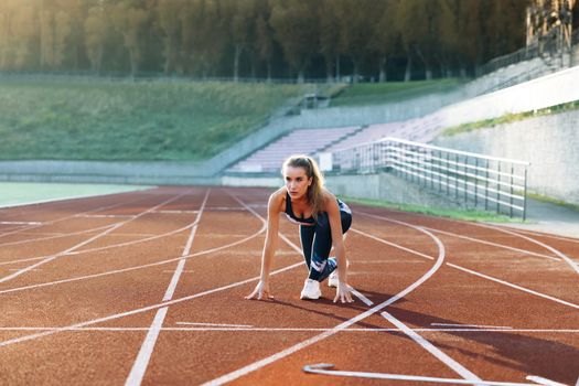 Female athlete starting her sprint on a running track. Runner taking off from the starting blocks on running track. Jogger activity. Female athlete. Sportswoman. Cardio exercises. Workout concept.