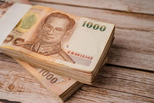 Stack of Thai baht banknotes on wooden background, business saving finance investment concept.