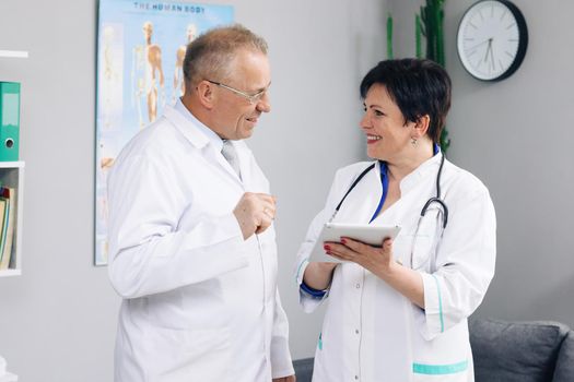 Two Hospital Partnership in medicine concept, healthcare tech. Medical team two old male and young female doctors wear white coats talk, use digital tablet.