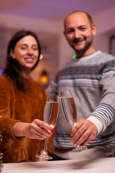 Joyful couple clinking glass of wine celebrating christmas traditional holiday in xmas decorated kitchen. Romantic happy family spending christmastime together enjoying winter season