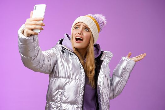 Upset bothered whining blond girl complaining cannot find right angle take selfie with cool sightseeing during vacation travelling abroad yelling smartphone pointing aside, purple background.