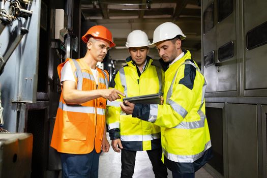 Three engineers men in uniform discuss use tablet, browsing building project indoor of construction site. Businessman worker, man male construction engineers or architects working people.