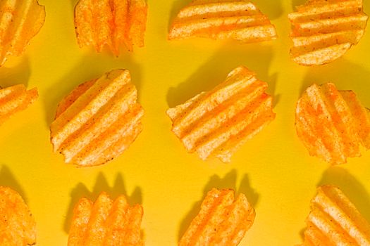 Ribbed potatoes snack with pepper on pastel yellow background. Ridged potato chips on yellow background. Collection. Flat lay.