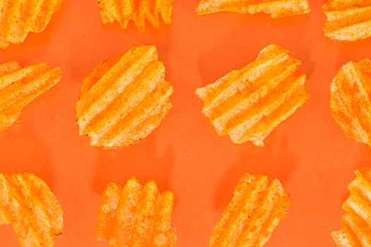 Ribbed potatoes snack with pepper on pastel orange background. Ridged potato chips on orange background. Collection. Flat lay.