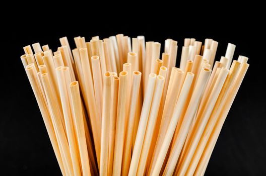 Wheat straw for drinking water in glass on black background. Zero waste concept.