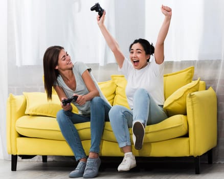 excited women home playing video games together. High resolution photo