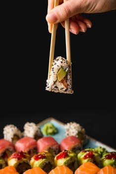 person holding sushi with chopsticks. High resolution photo