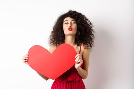 Romantic woman in dress showing big red heart, pucker lips for kiss and express love, express sympathy, white background.
