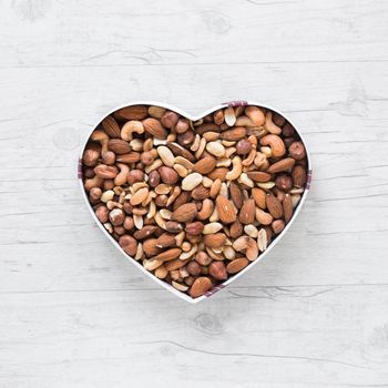 top view healthy dryfruits heart shape wooden desk. High resolution photo