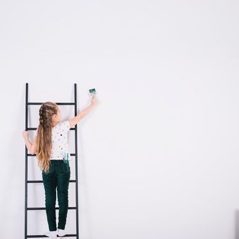 little girl ladder painting wall. High resolution photo