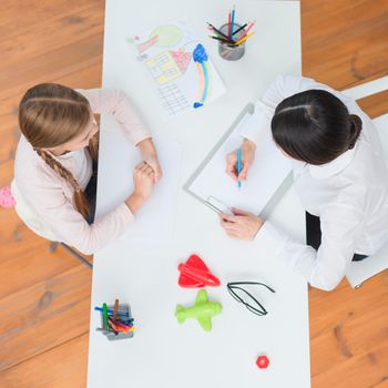 elevated view little girl talking her female psychologist taking note clipboard. High resolution photo