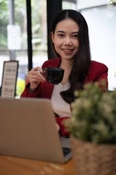 Portrait of beautiful fund managers sitting on chair with cup of cooffee and tablet on wooden desk in cafe shop