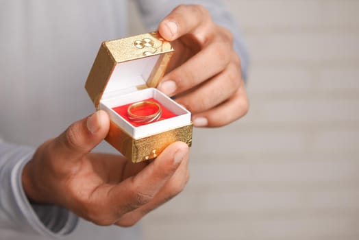 young man hold a wedding ring in a box .